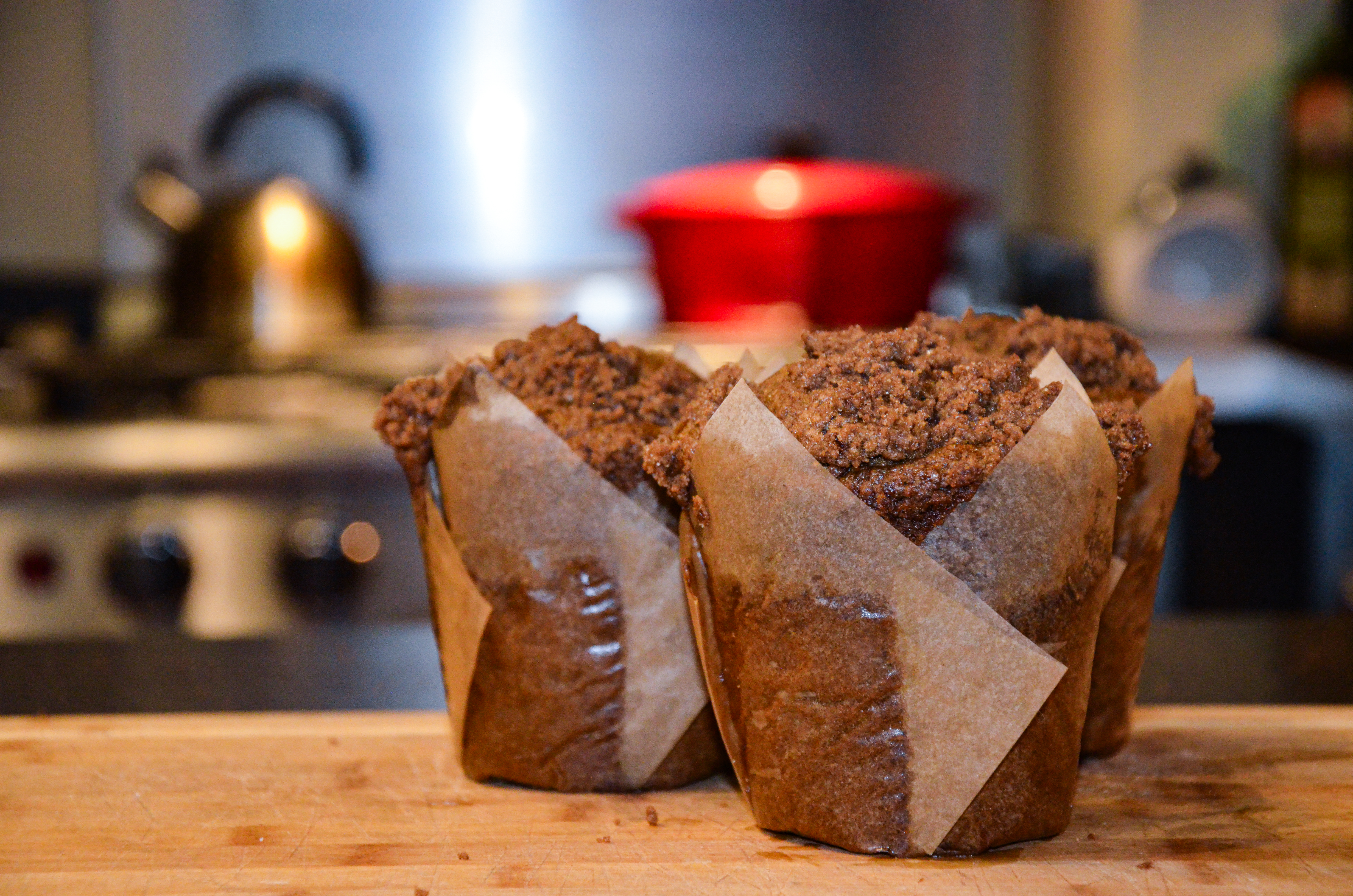 Three pumpkin streusel muffins with a red dutch oven in the background